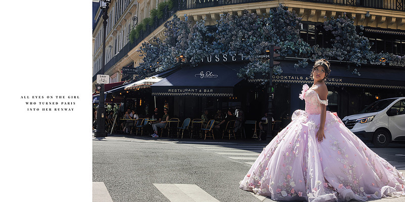 Quinceañera girl in a pink floral ballgown standing confidently on Rue de Rivoli in Paris, with a Parisian café and blue floral décor in the background.