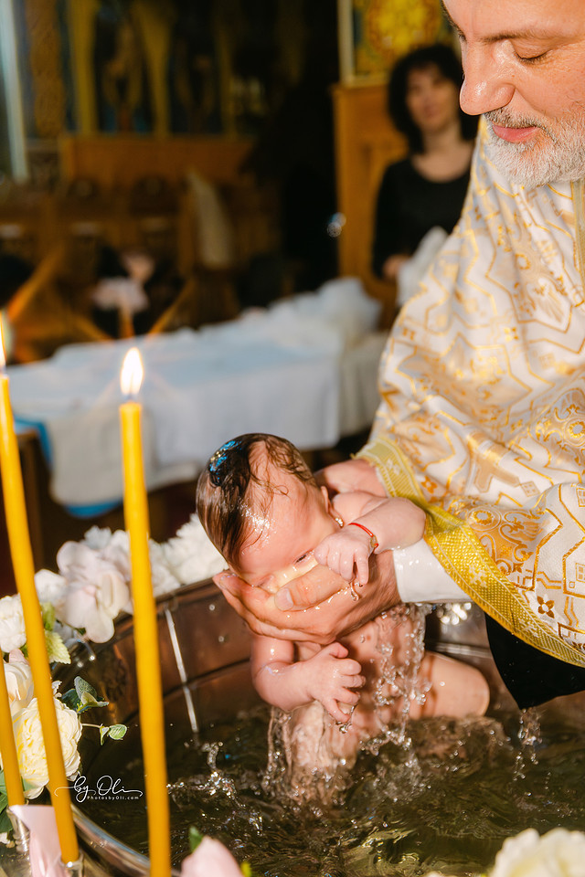 Momentul botezului crestin ortodox al Victoriei, scufundare in cristelnita la Biserica Sf. Nicolae Timisoara, locatie apreciata pentru pictura si arhitectura. Fotografie artistica surprinsa de unul dintre cei mai apreciati fotografi de botez din Timisoara, poveste vizuala cu ritual, lumina si compozitie puternica.