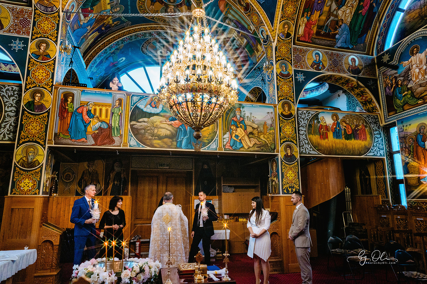 Fotografie artistica slujba botez in Biserica Sf. Nicolae Timisoara, locatie renumita pentru pictura si arhitectura. Invitata privind de sus ritualul, scena ampla surprinsa de unul dintre cei mai apreciati fotografi de botez din Timisoara, poveste vizuala cu lumina si compozitie puternica.
