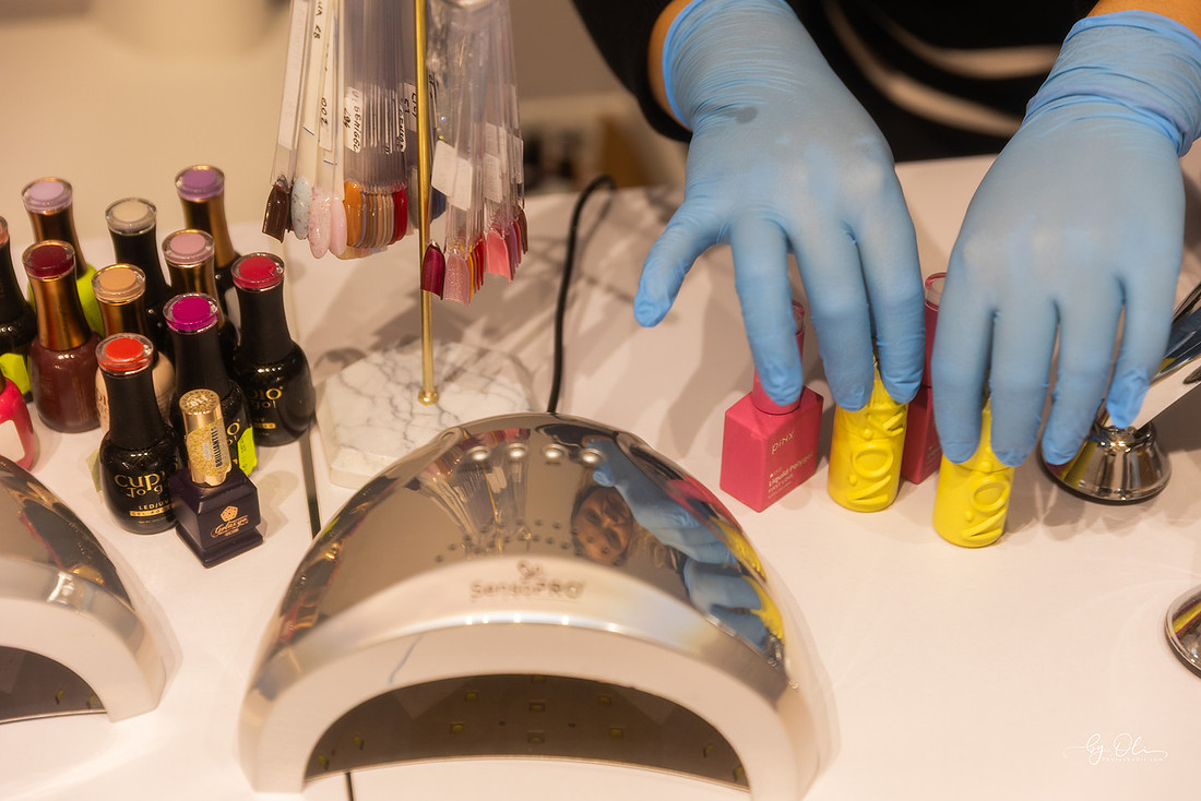 Detalii din salonul L Beauty: oje colorate, lampa UV si maini protejate, surprinse intr-o atmosfera calda si profesionala.