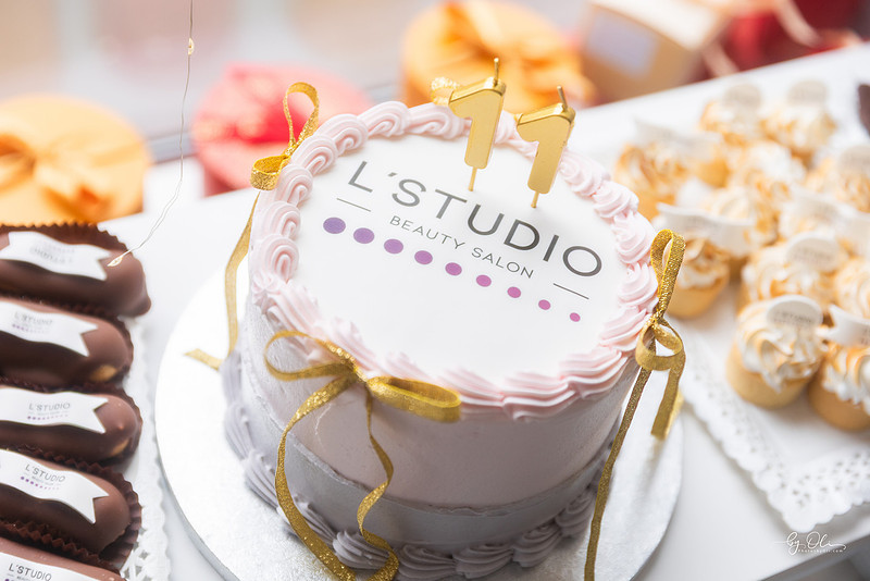 Tort aniversar cu logo-ul L Studio, decorat elegant, intr-un cadru festiv si luminos.