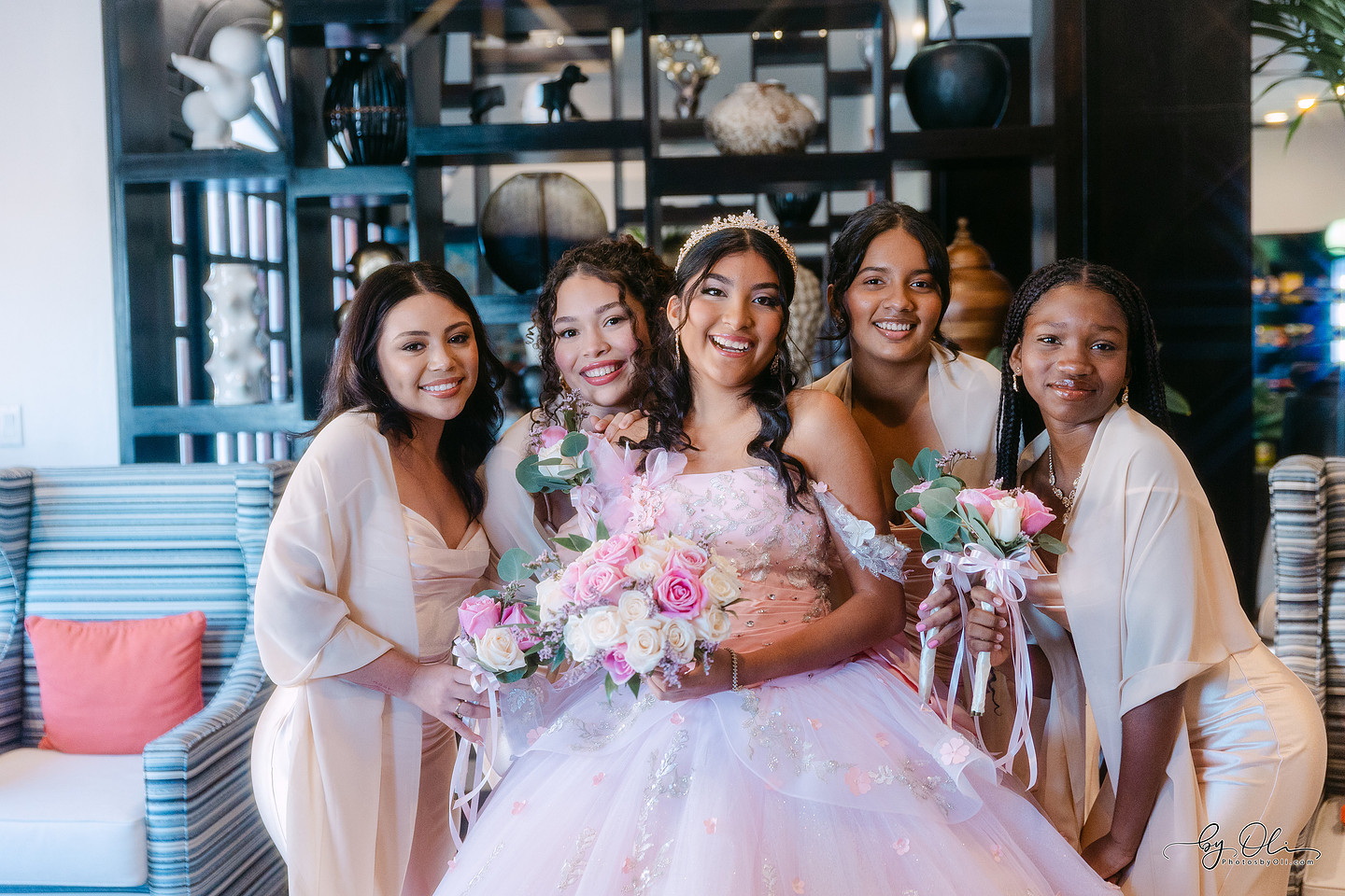 Chelsea Monique Alfaro smiling with her friends during a quinceañera photo session at the Biltmore Hotel in Belize, celebrating together in the hotel lobby.