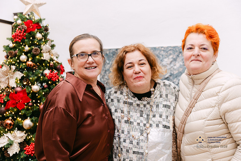 Portret de grup cu trei doamne, simbol al prieteniei si comunitatii, fotografiate langa bradul de Craciun, la Intalnirea de Craciun – Casa de Asigurari a Avocatilor, Filiala Timis.