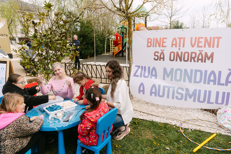 Copii si adulti la o activitate de lucru manual in aer liber, langa bannerul Ziua Mondiala a Autismului 2026, Timisoara – fotografie Olivera Banda