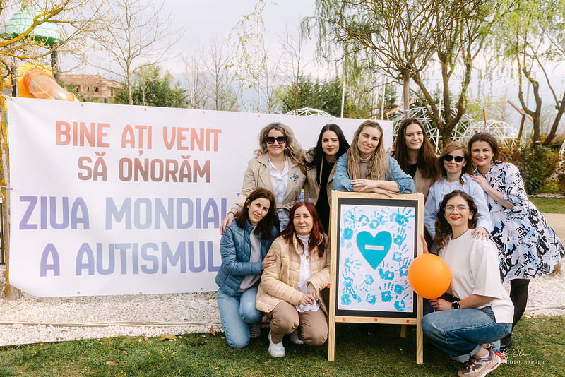 Echipa de organizatori femei pozand langa bannerul Ziua Mondiala a Autismului Timisoara, dedicare si implicare comunitara, Photos by Oli Timisoara