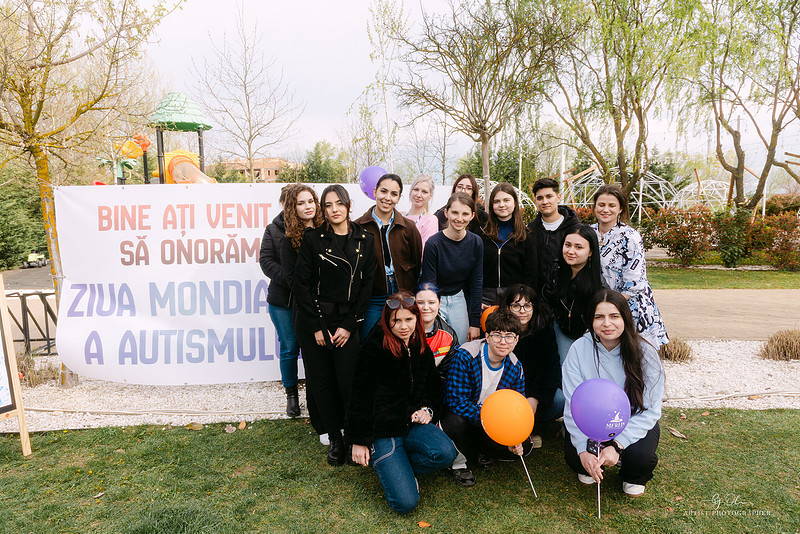 
Echipa de organizatori femei pozand langa bannerul Ziua Mondiala a Autismului Flonta Timisoara, dedicare si implicare comunitara, Photos by Oli Timisoara